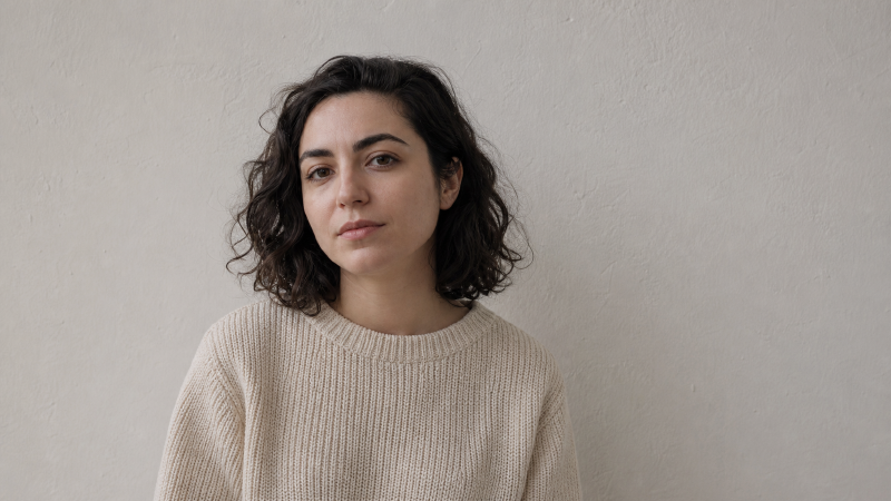 米色毛衣的人坐在白墙前,主体与背景亮度接近,人物陷进背景